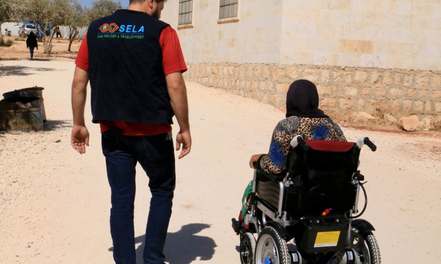 A woman in a wheelchair next to a worker of the Sela humanitarian organization in a camp in northern Syria - 5 October 2022 (Sela org/Twitter)