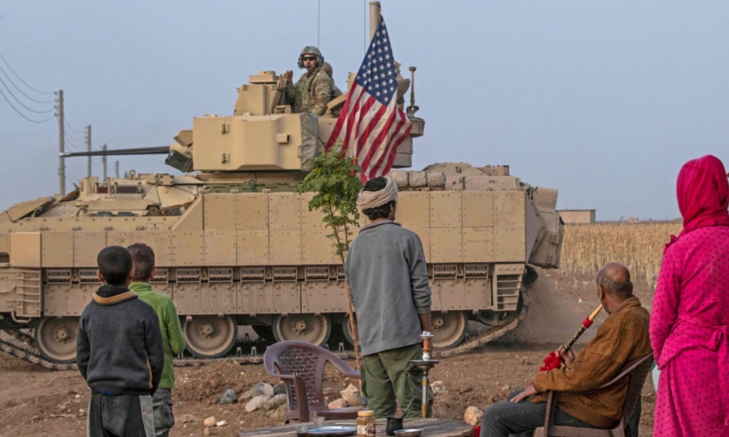An American tank passes in front of a local family in northeastern Syria (AFP)