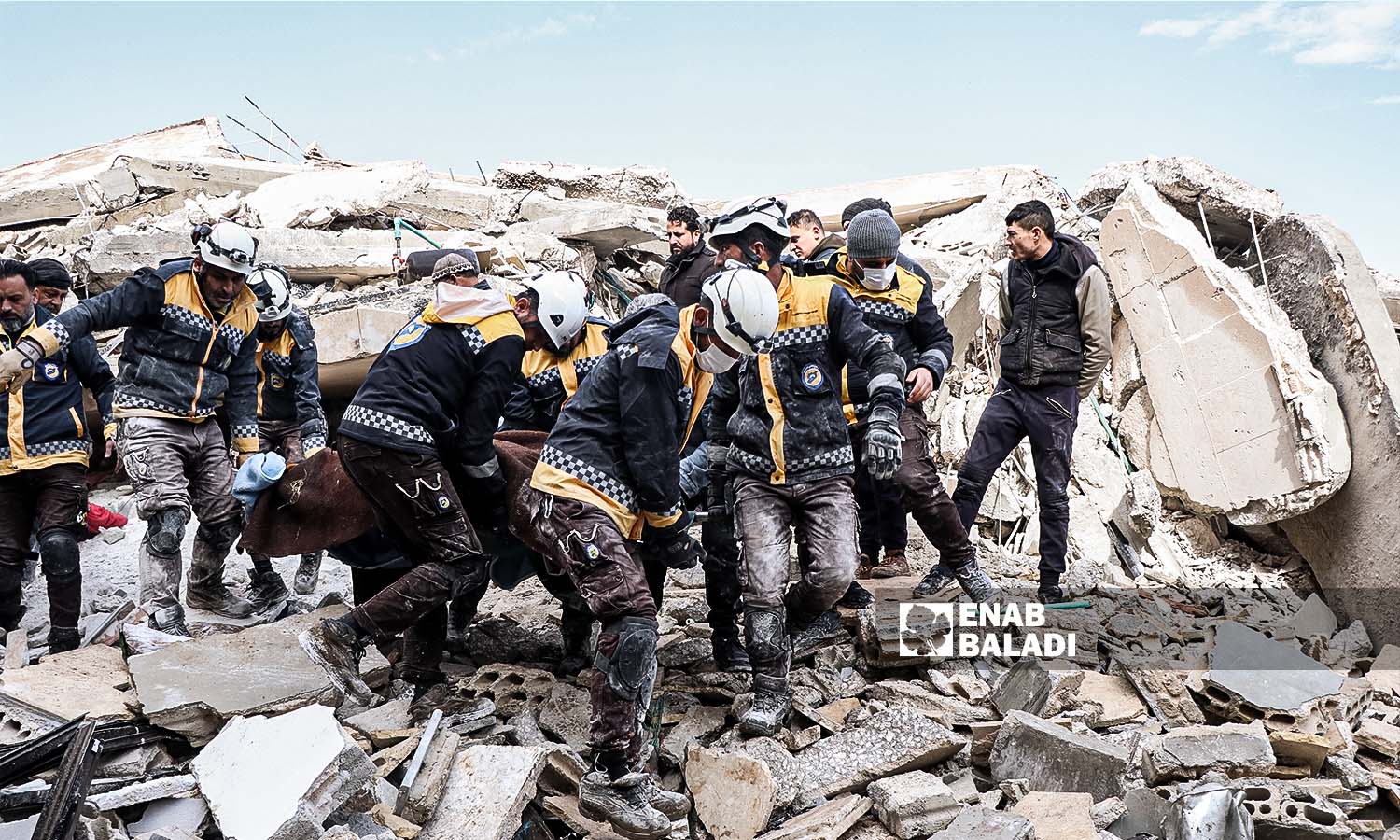 Volunteers from the Syria Civil Defense (SCD) teams carry one of the injured who was stuck under the rubble in Azmarin village following the earthquake that struck the northwestern Syrian region - February 7, 2023 (Enab Baladi/Mohammad Nasan Dabel)
