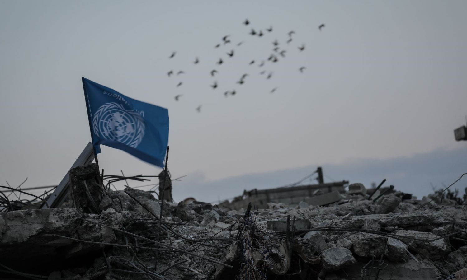 The UN’s flag is upside down over the rubble of a destroyed building in the town of Jindires in the northern countryside of Aleppo, denouncing the delay in response following the earthquake that struck Turkey and four regions of Syria - February 11, 2023 (Facebook/Malik Abu Obeida)
