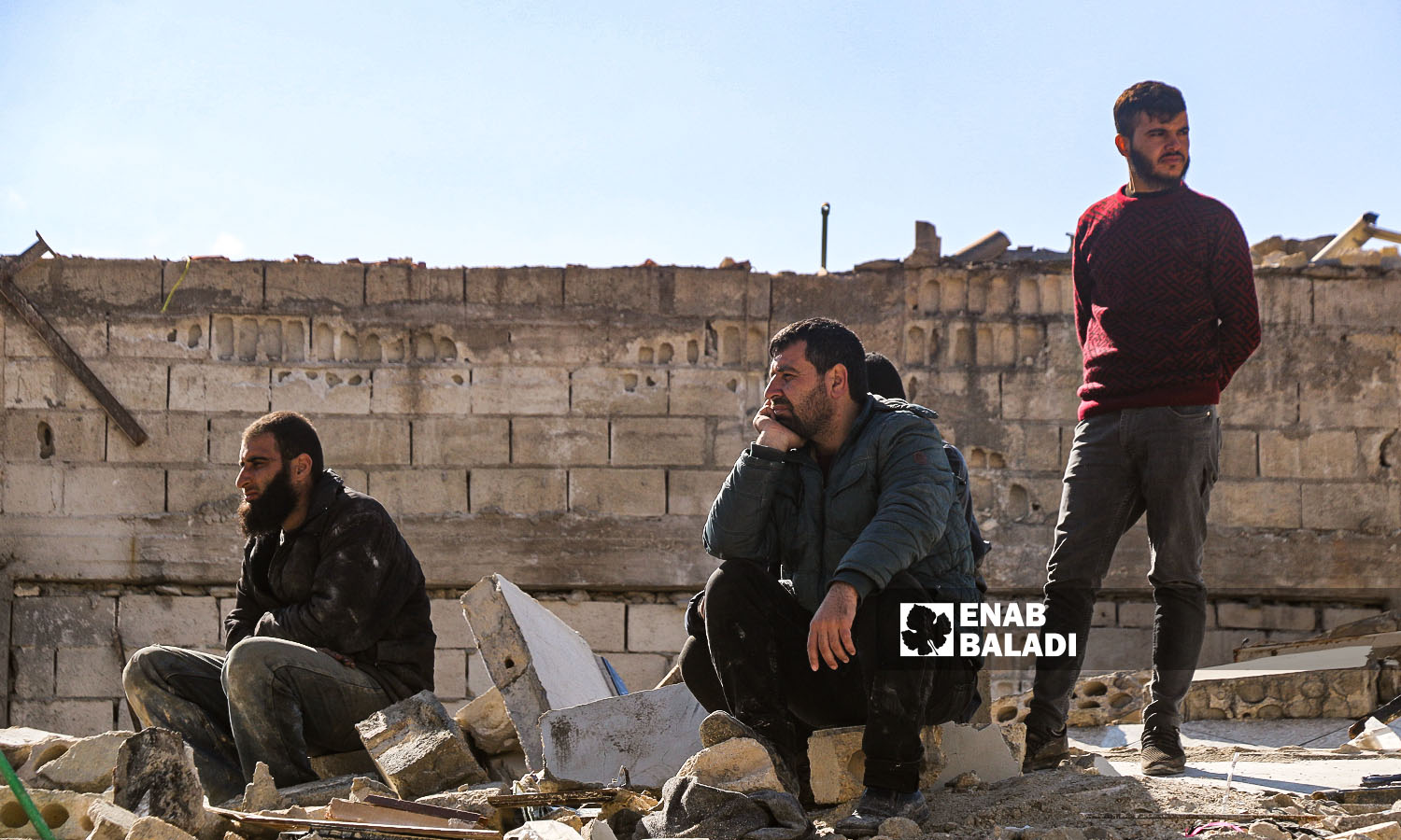 Syrian men stand on the rubble of one of the houses of Armanaz town destroyed by the earthquake that hit the northwestern Syrian region - February 7, 2023 (Enab Baladi/Iyad Abdul Jawad) 
