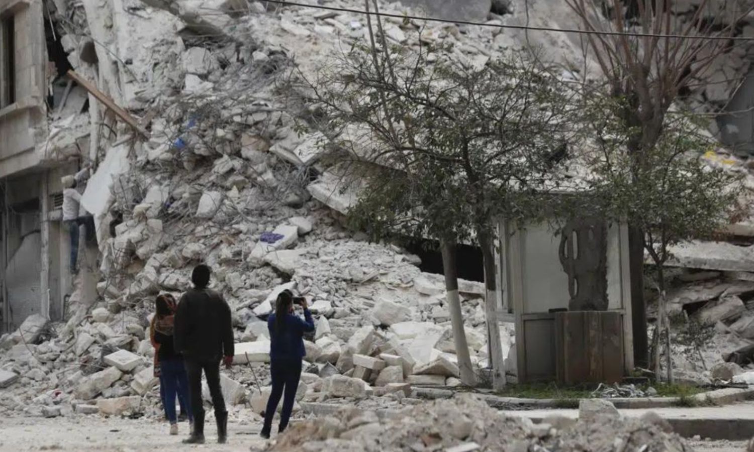People standing near a quake-destroyed building in northern Aleppo city - February 27, 2023 (AP)