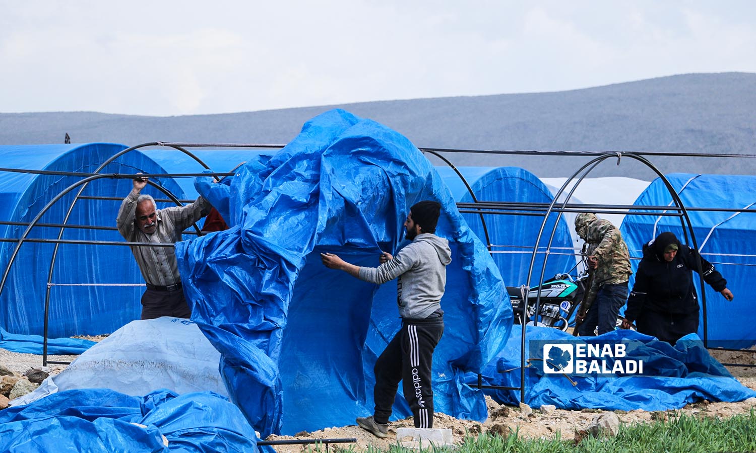 Displaced people trying to repair their tents after they were damaged by an air storm in Jisr al-Shughour region, west of Idlib - March 6, 2023 (Enab Baladi/Mohammad Nasan Dabel)