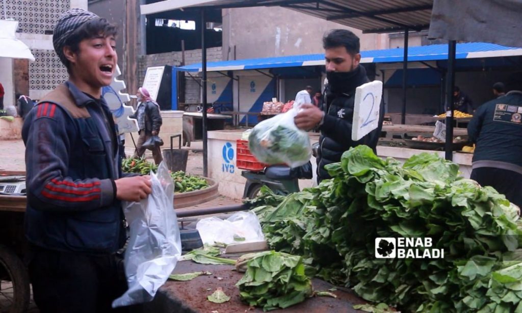 A young man selling vegetables in the local market in the northwestern city of Idlib - March 2023 (Enab Baladi/Anas al-Khouli)
