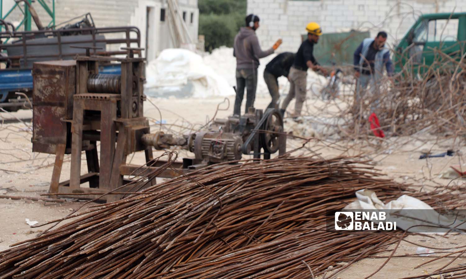 Construction workers straighten iron bars collected from quake-destroyed buildings to recycle them in Salqin city in Idlib countryside - April 30, 2023 (Enab Baladi/Iyad Abdul Jawad)
