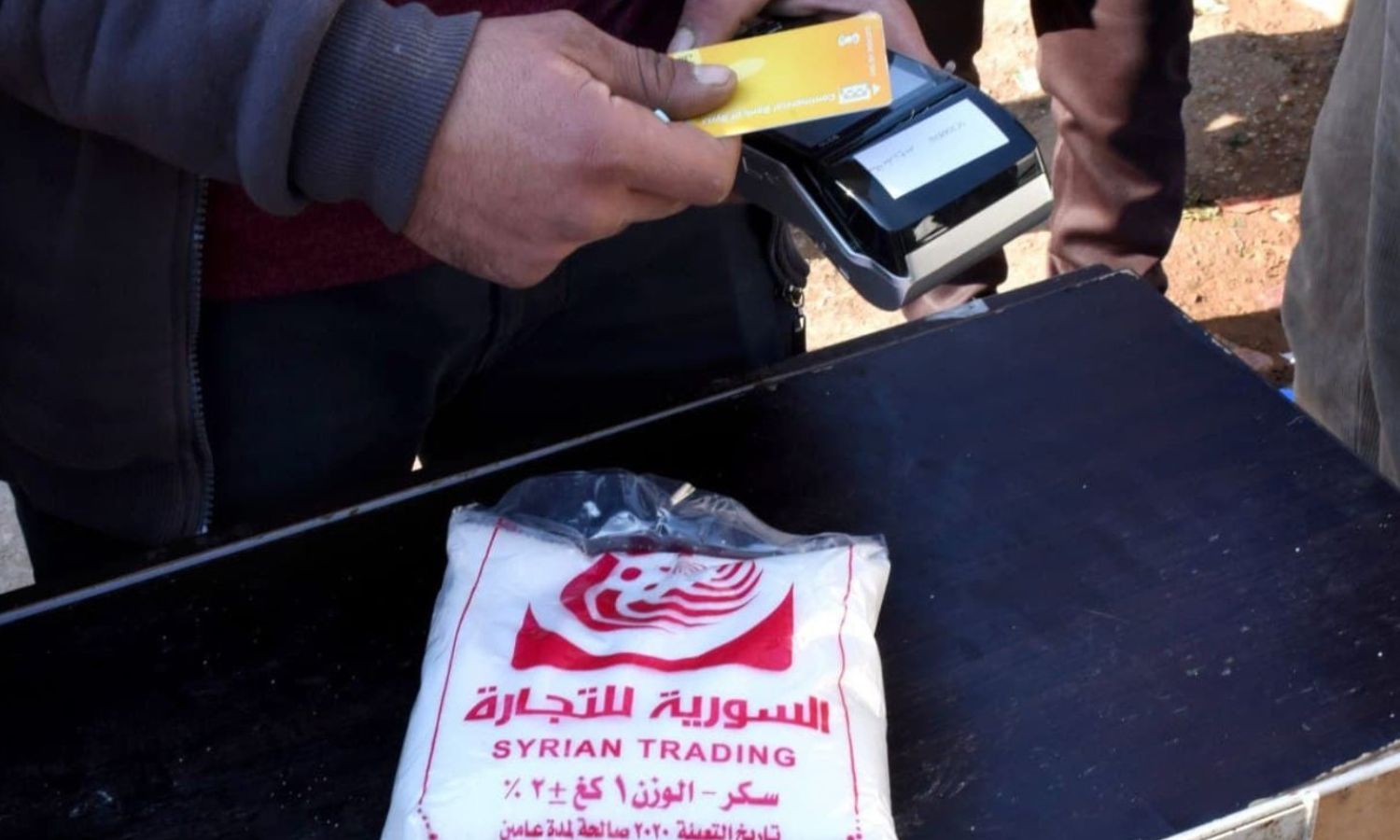 Selling sugar through the government subsidy card, known as the smart card, in regime-held areas. 2021 (Al-Watan newspaper)