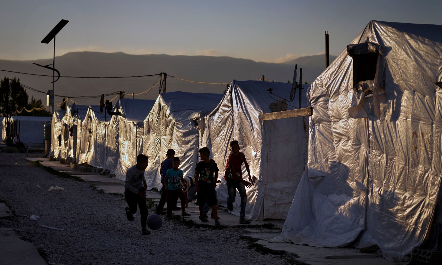 Syrian children play football next to their tents in a refugee camp in the town of Bar Elias in the Bekaa Valley, Lebanon - July 7, 2022 (AP)