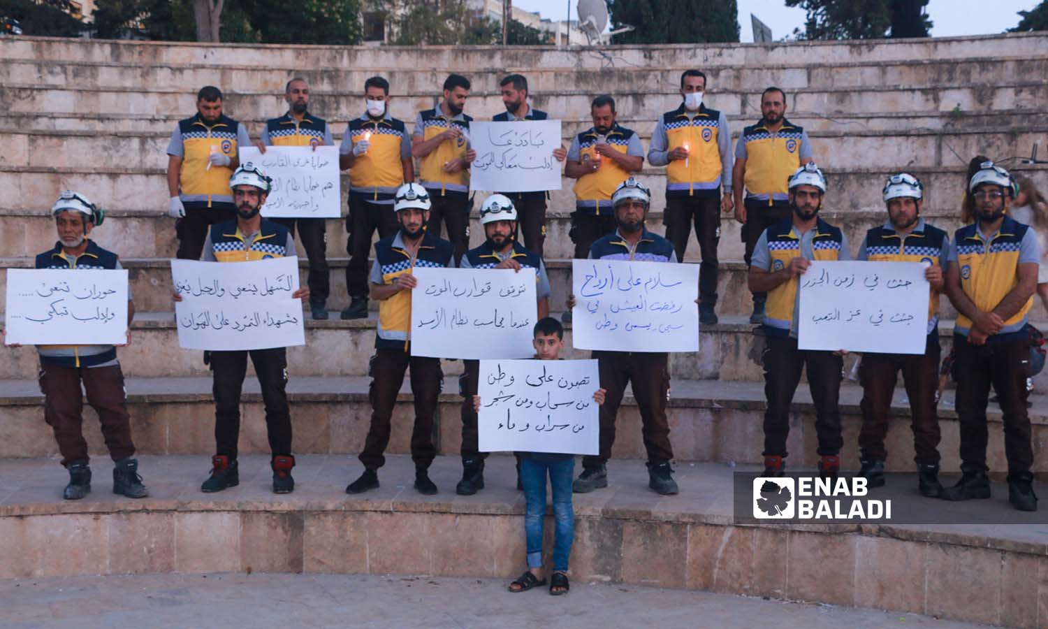 Syria Civil Defense volunteers in the city of Idlib hold banners calling for an investigation into the reasons for the sinking of a refugee boat on the coast of Greece - June 18, 2023 (Enab Baladi/Anas al-Khouli)
