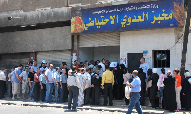 Syrian citizens line up to get subsidized government bread from al-Adawi bakery in Damascus (AFP)