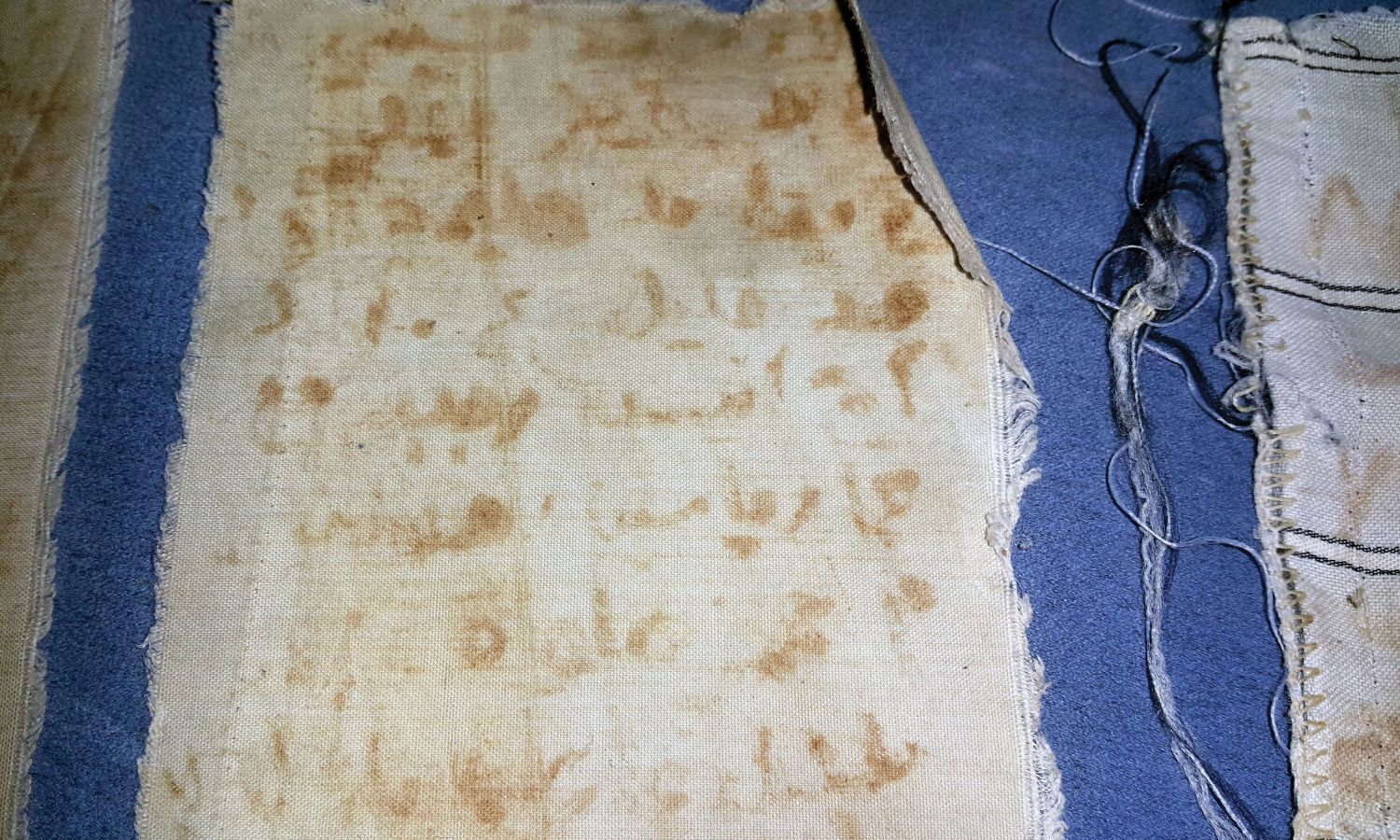 Five strips of ripped cloth with the names list which Mansour al-Omari smuggled out of prison and contacted the families of the detainees whose names were written on the cloth to inform them of the whereabouts of their loved ones and that they were alive. © Enab Baladi/ Mansour al-Omari.