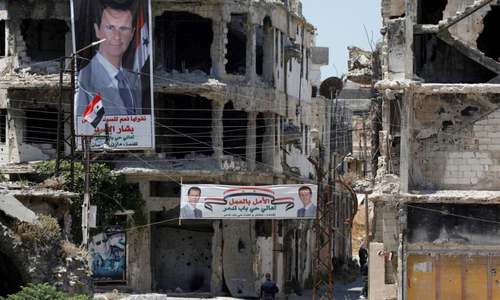 Two banners calling for Bashar al-Assad’s election were hung on the destroyed buildings in central Homs city (Reuters)