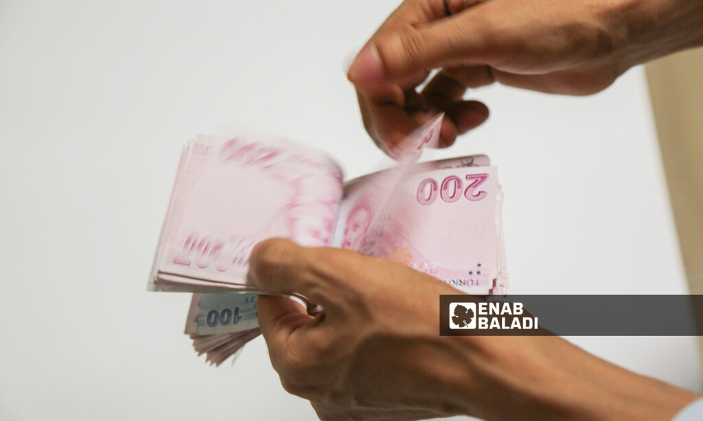 A Syrian man counts a bundle of Turkish money to send to his family in Syria - October 7, 2023 (Enab Baladi/Abdulmoeen Homs)