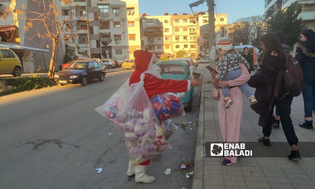 A man dressed as Santa Claus distributes gifts to children in the city of Latakia – December 21, 2023 (Enab Baladi/Linda Ali)