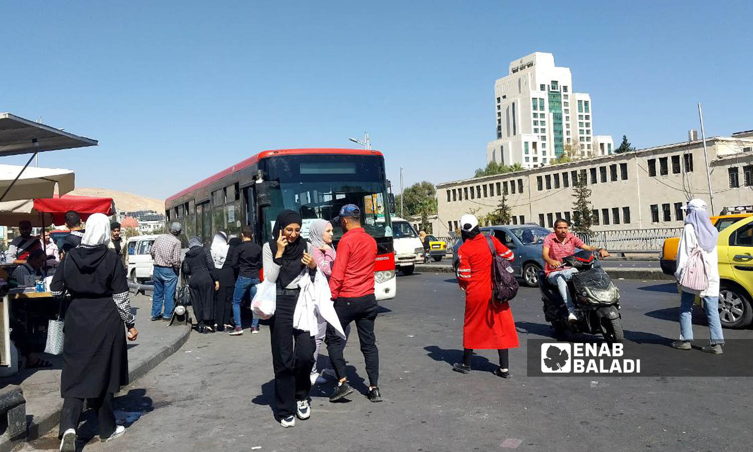 A group of people board a bus on the President’s Bridge (Jisr al-Rais) in Damascus - October 26, 2023 (Enab Baladi/Sarah al-Ahmad)

