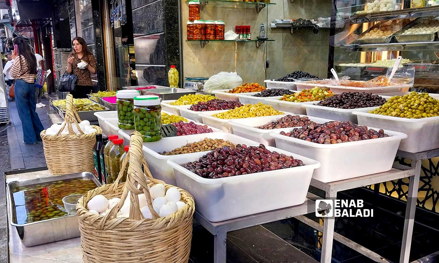 A food store selling different types of olives in al-Shaalan market in Damascus - October 26, 2023 (Enab Baladi/Sarah al-Ahmad)
