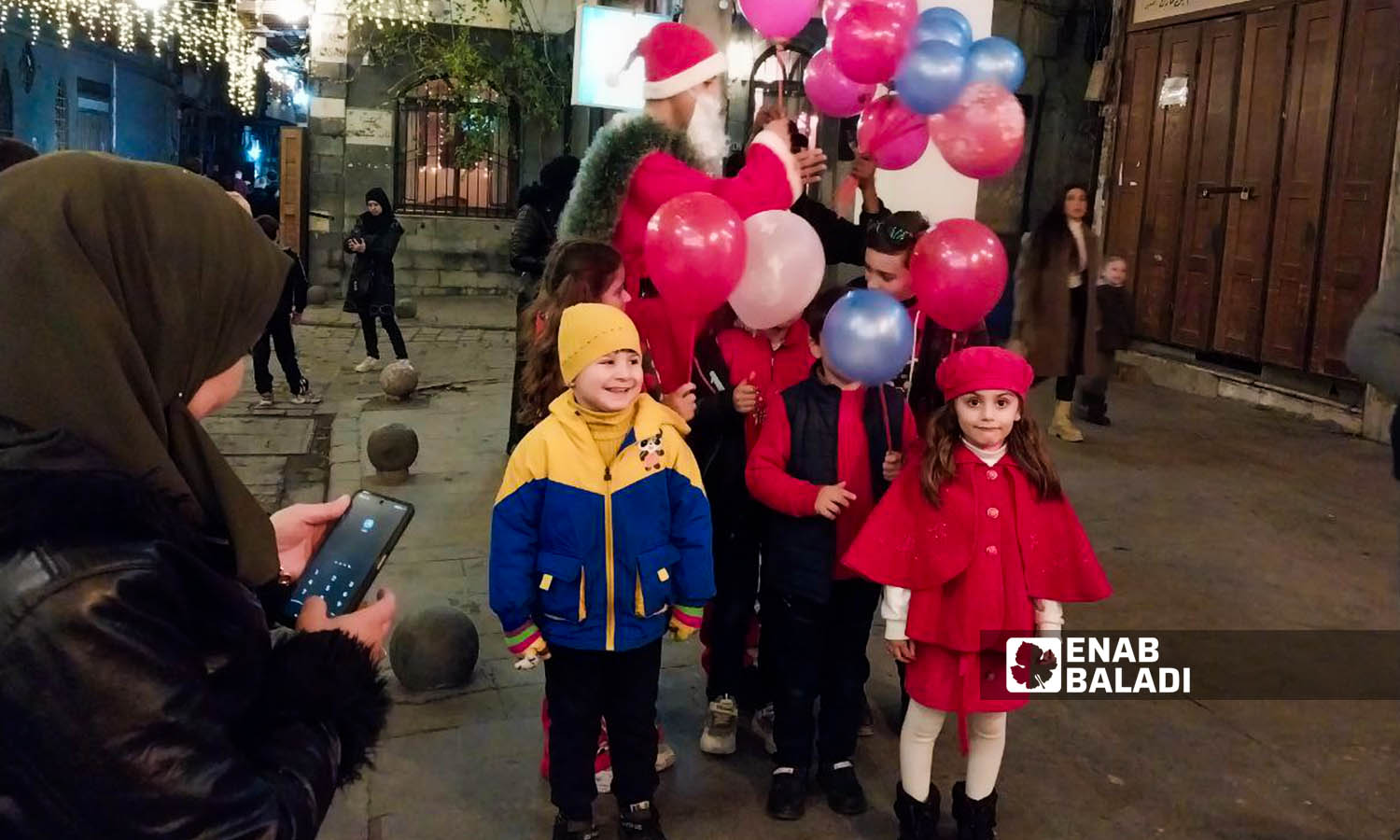 Children dressed in red clothes in celebration of Christmas in Bab Sharqi neighborhood in Damascus - December 26, 2023 (Enab Baladi/Sarah al-Ahmad)
