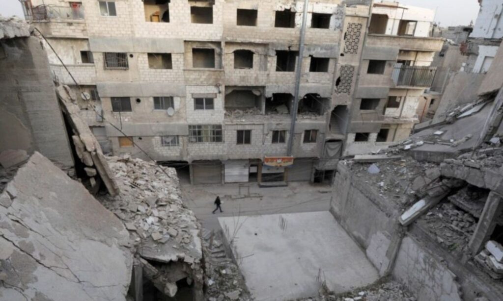 A man walks near damaged buildings in Douma city in the Eastern Ghouta suburbs - March 9, 2021 (Reuters)