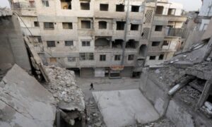 A man walks near damaged buildings in Douma city in the Eastern Ghouta suburbs - March 9, 2021 (Reuters)