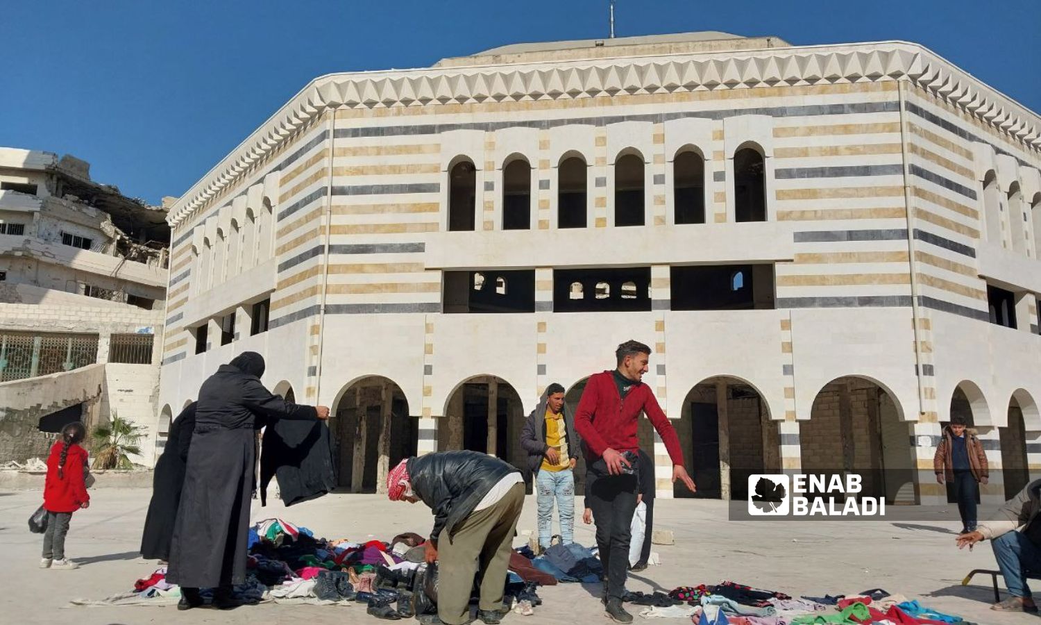 A man selling clothes in the al-Jalaa Street in front of the Great Mosque in Douma city, rural Damascus - January 22, 2024 (Enab Baladi/Sarah al-Ahmad)
