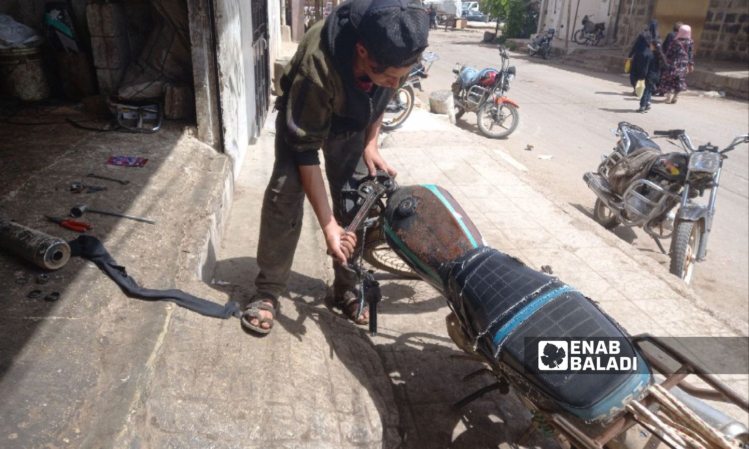 A child repairs a motorbike in the city of Tafas in Daraa governorate, May 27, 2023 (Enab Baladi/Halim Muhammad)