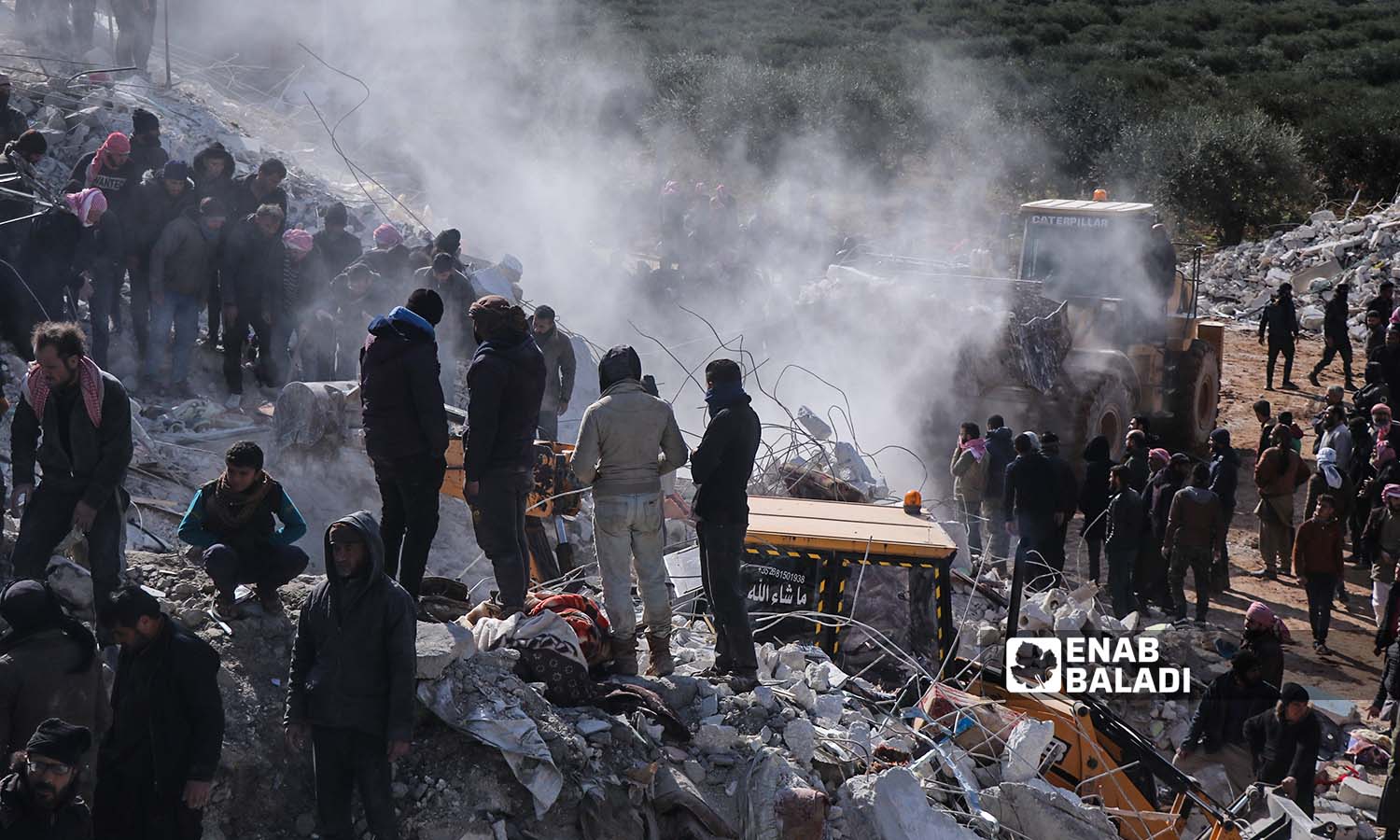 Rescue teams and volunteer residents search for victims and survivors amidst the rubble of collapsed buildings following an earthquake that struck northwestern Syria in the village of Basnia near the city of Harem on the Syrian-Turkish border - February 7, 2023 (Enab Baladi/Mohammad Nasan Dabel)