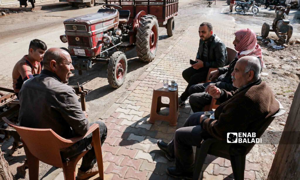 Syrian men sit in a street in Jindires city a year after the earthquake disaster that affected southern Turkey and northwestern Syria - February 6, 2024 (Enab Baladi/Dayan Junpaz)