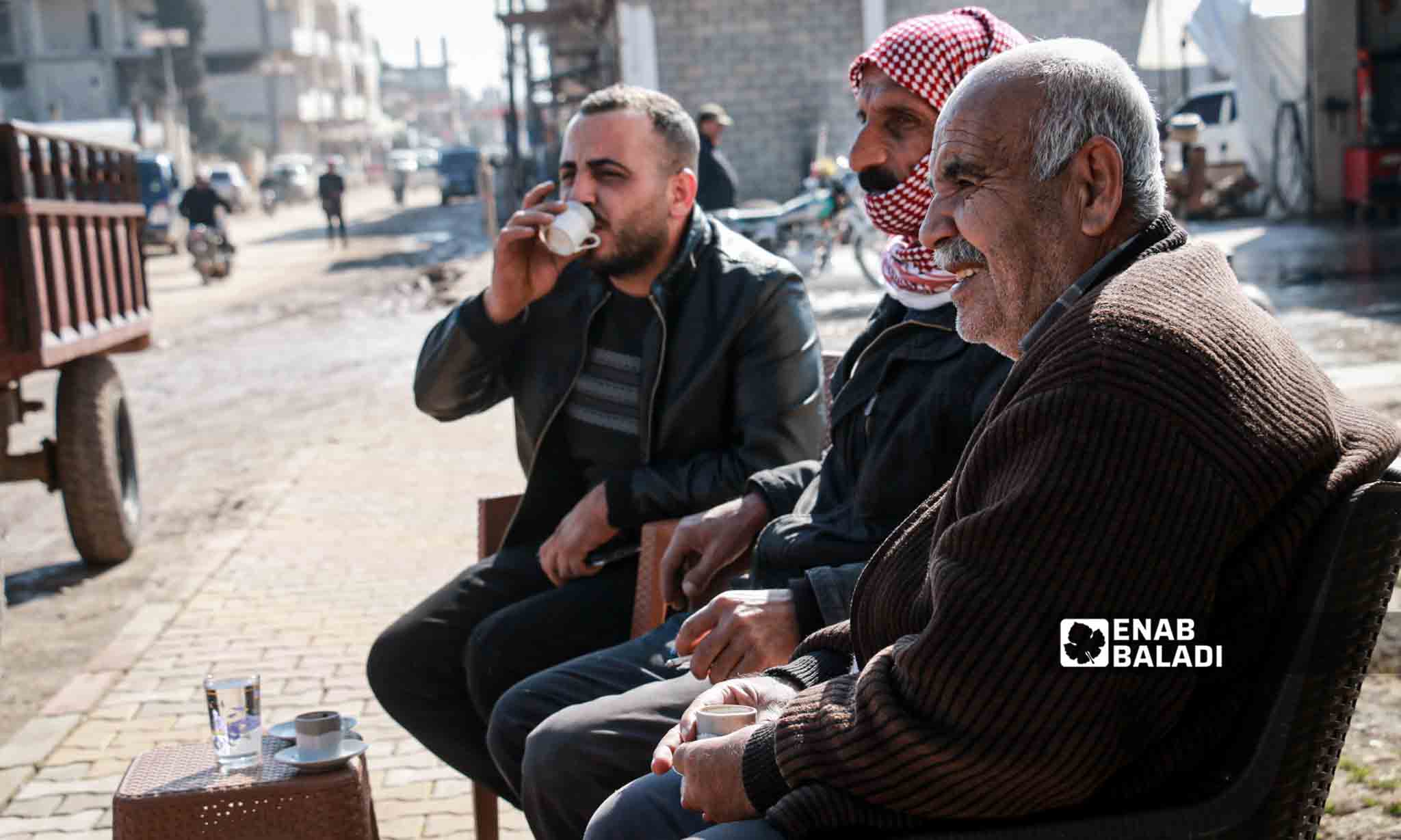 Syrian men sit in a street in Jindires city a year after the earthquake disaster that affected southern Turkey and northwestern Syria - February 6, 2024 (Enab Baladi/Dayan Junpaz)
