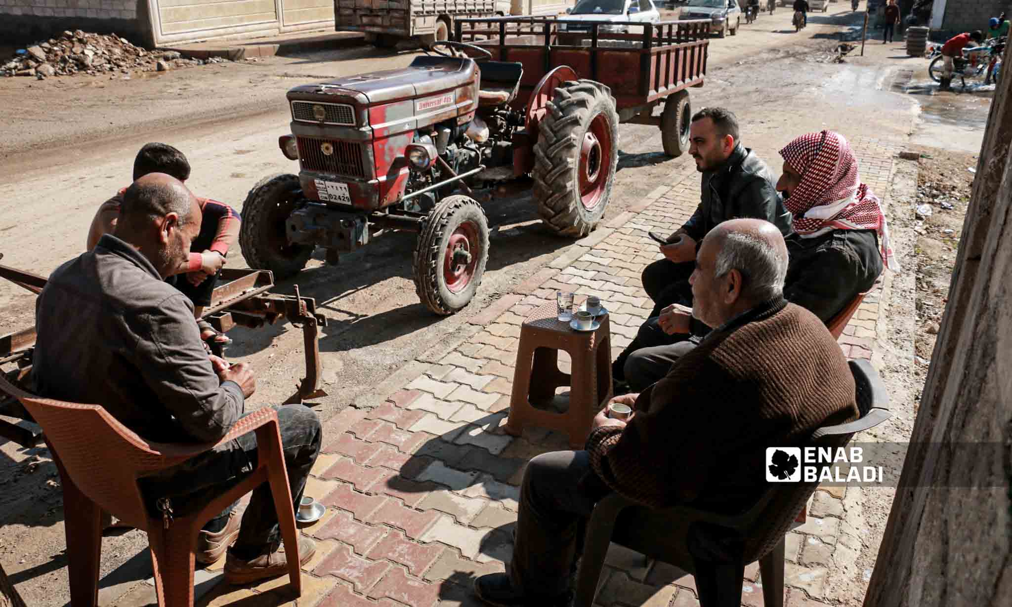 Syrian men sit in a street in Jindires city a year after the earthquake disaster that affected southern Turkey and northwestern Syria - February 6, 2024 (Enab Baladi/Dayan Junpaz)
