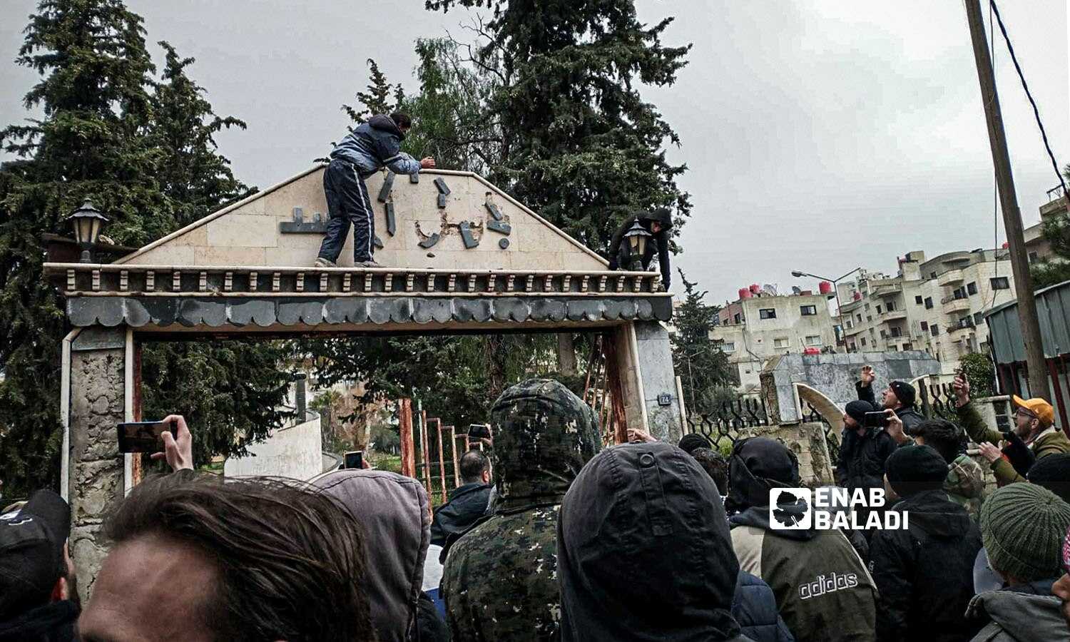 Protesters remove the name of Bassel al-Assad from the entrance of a park in As-Suwayda governorate in southern Syria - February 19, 2024 (Enab Baladi)
