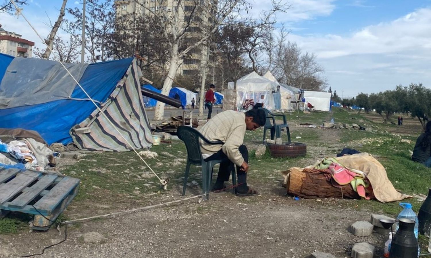 A child suffering from a mental health condition is restrained by his foot outside his family's tent at an unofficial displacement site in Turkey - March 2023 (Amnesty International)