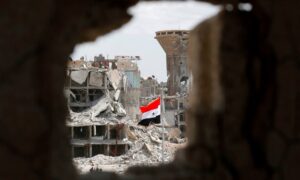 The Syrian regime's flag at the entrance of al-Hajar al-Aswad district in the capital, Damascus - May 24, 2018 (AFP)