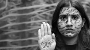 A young woman protests against violence toward women and girls by writing messages on her face demanding an end to the violence (Shutterstock)