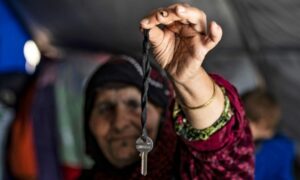 A Syrian woman, displaced from Ras al-Ain and carrying the key to her home after it was seized by Turkey-affiliated military factions – August 10, 2020 (AFP)
