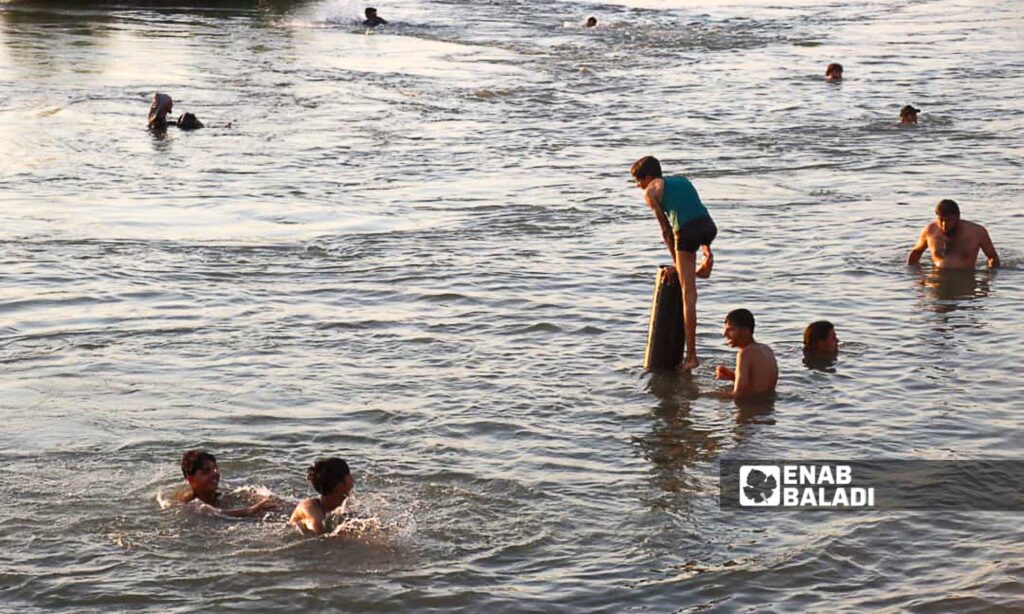 Young men swim in the Euphrates River in the countryside of Deir Ezzor, eastern Syria - July 20, 2024 (Enab Baladi/Obadah al-Sheikh)