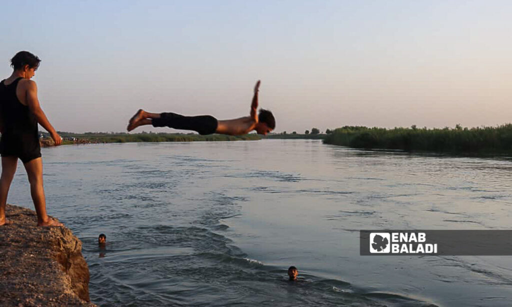 Young men swim in the Euphrates River in the countryside of Deir Ezzor, eastern Syria - July 20, 2024 (Enab Baladi/Obadah al-Sheikh)