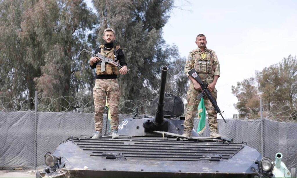 A fighter from the People's Protection Units (right) alongside a fighter from the Deir Ezzor Military Council (left) during celebrations marking the control of the town of al-Baghouz in eastern Deir Ezzor - March 23, 2024 (Syrian Democratic Forces)