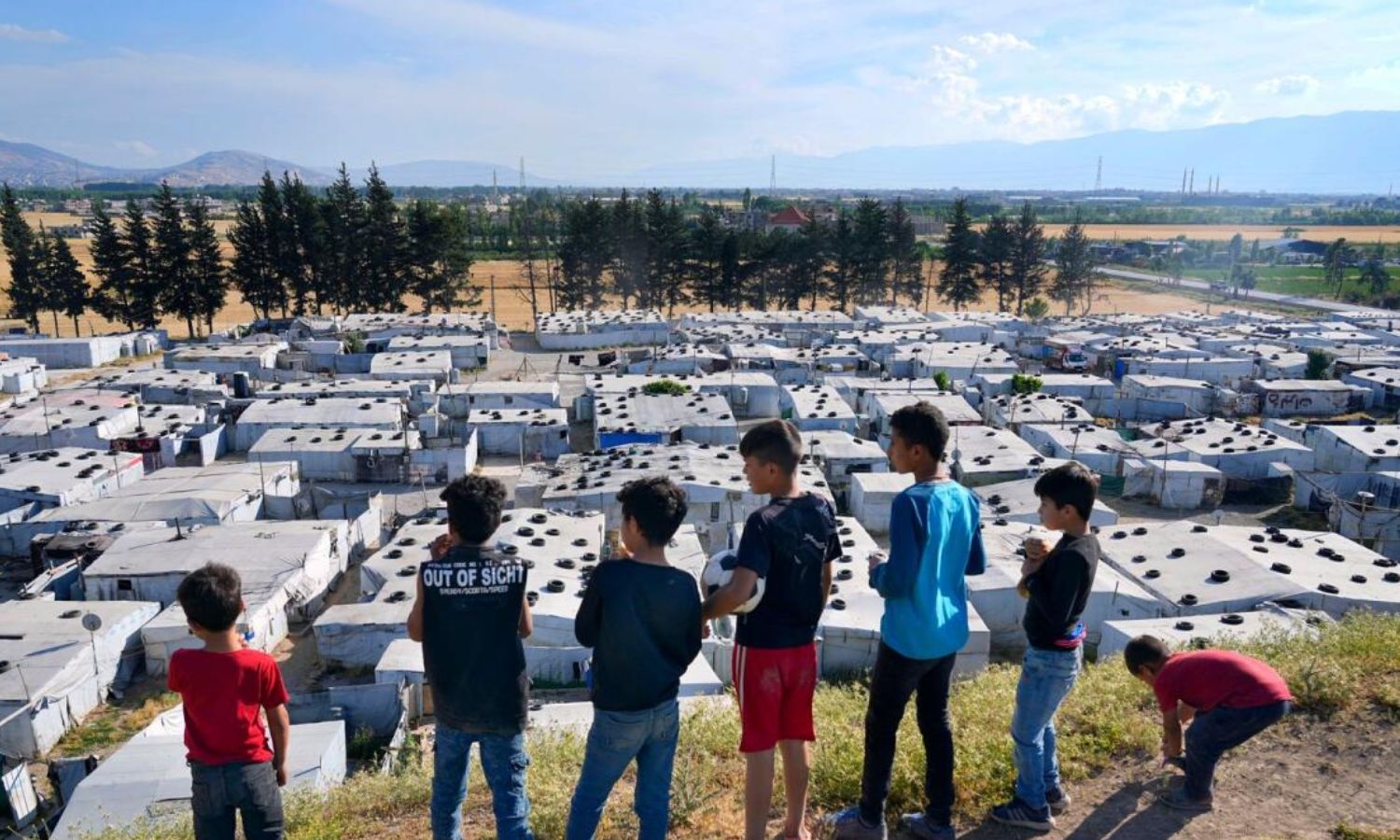 Syrian children stand on a hill above a refugee camp in the town of Bar Elias in the Bekaa Valley, Lebanon - June 13, 2023 (AP)