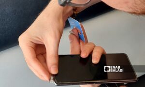 A young man places a SIM card into his mobile phone in Azaz - October 4, 2024 (Enab Baladi/Dayan Junpaz)