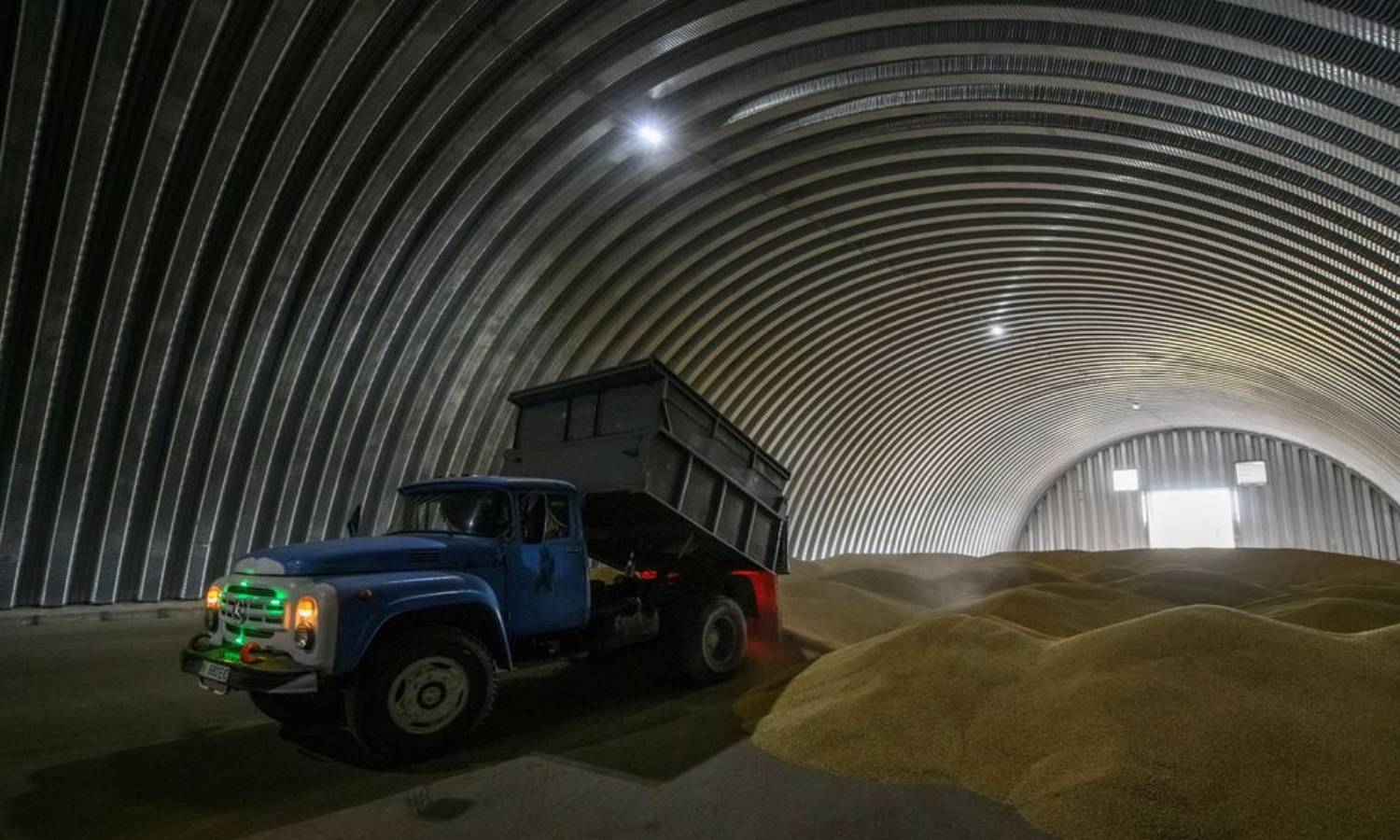 An employee empties wheat grains inside a warehouse in a Ukrainian village - August 9, 2022 (Reuters)