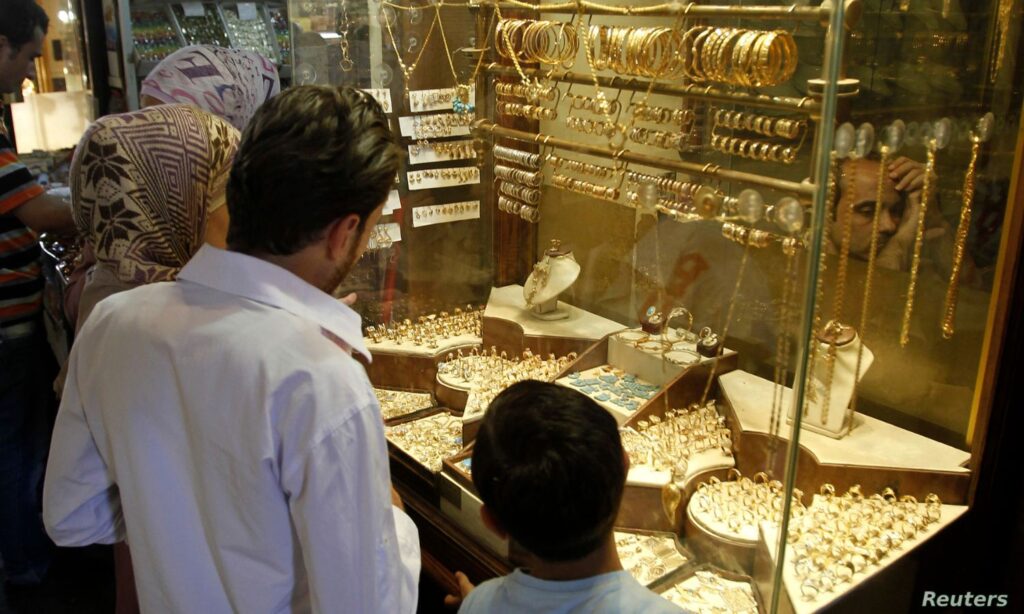 A Syrian family stands in front of a gold shop in Damascus - September 2024 (Reuters)