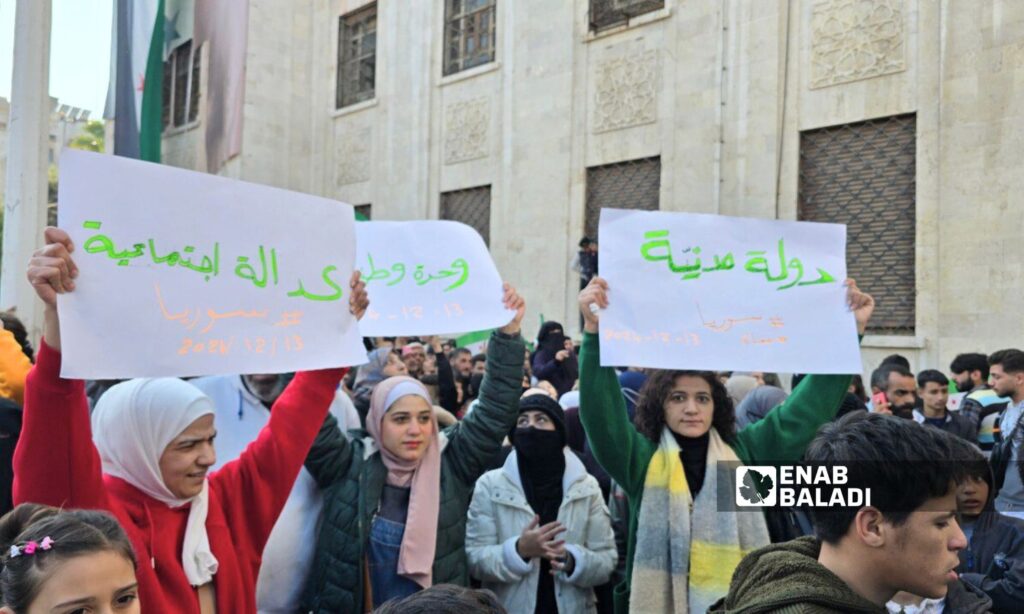 Women holding banners at the celebration of Bashar al-Assad's fall in Hama - December 13, 2024 (Enab Baladi/Iyad Abdul Jawad)