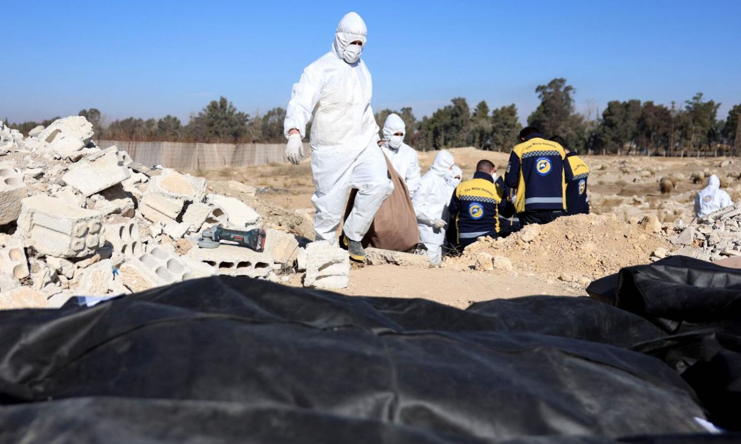 Members of the Syria Civil Defence are preparing to transfer bodies found in a mass grave in Damascus - December 16, 2024 (AFP)