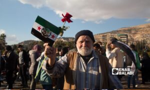 A man carrying the flag of the Syrian revolution stands among thousands of Syrians celebrating the fall of the regime in Damascus – December 13, 2024 (Enab Baladi/Dayan Junpaz)