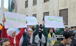 Women holding signs at a celebration marking the fall of Assad regime in Hama - December 13, 2024 (Enab Baladi/Iyad Abdul Jawad)