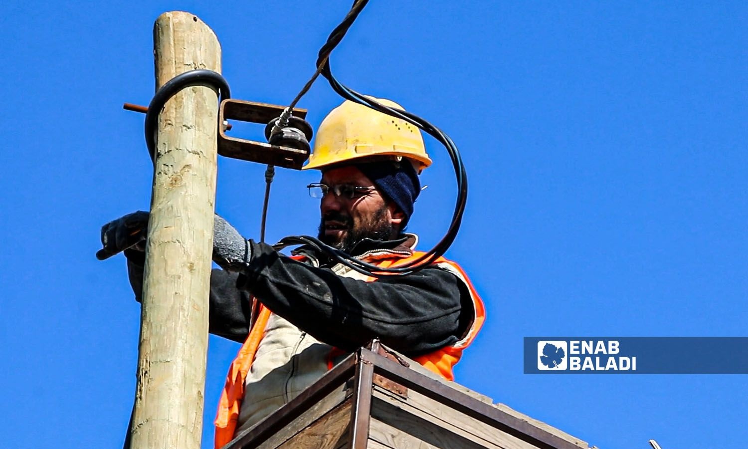 An employee at the electricity company in northern Aleppo during the maintenance of electrical wires - February 2022 (Enab Baladi)