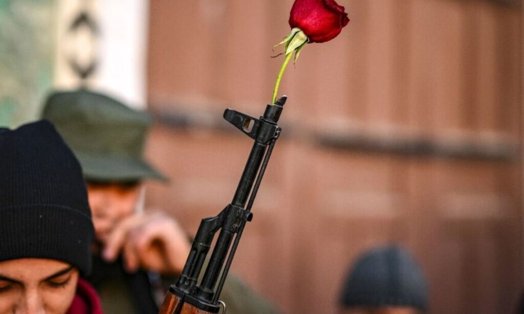 A fighter from the Military Operations Administration that overthrew Assad's regime holds a rose in the muzzle of his rifle at the Umayyad Mosque in Damascus - December 13, 2024 (AFP)