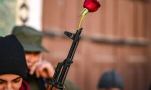 A fighter from the Military Operations Administration that overthrew Assad's regime holds a rose in the muzzle of his rifle at the Umayyad Mosque in Damascus - December 13, 2024 (AFP)
