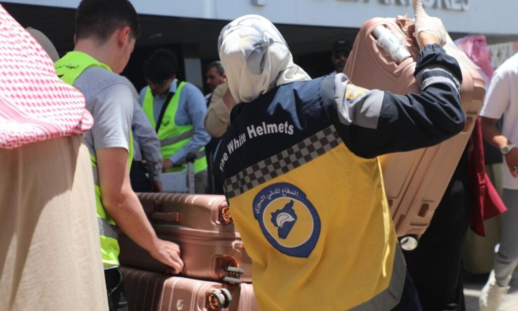 A volunteer in the Syria Civil Defence assists Syrian pilgrims in transporting their luggage - May 25, 2025 (Syria Civil Defence)