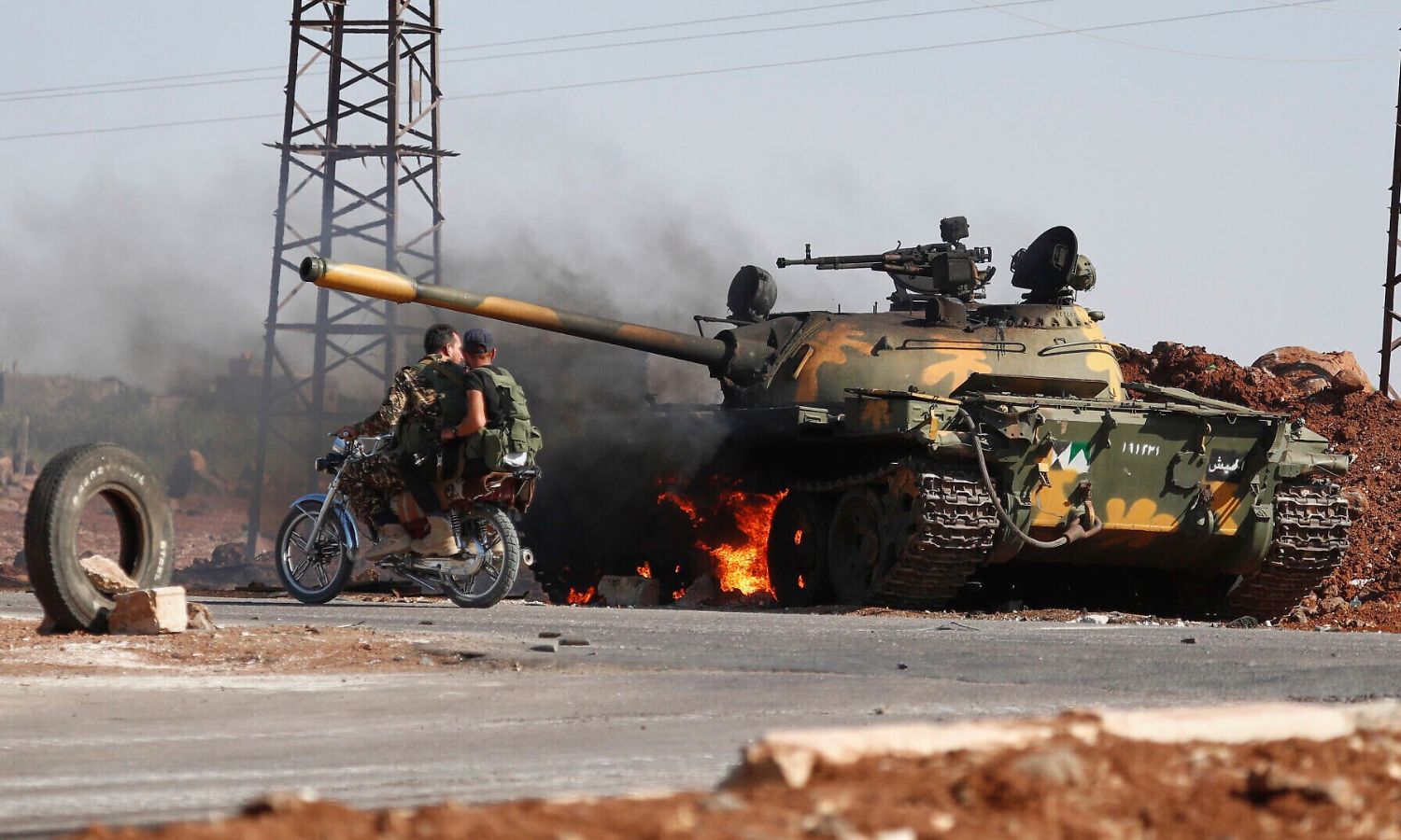Syrian government soldiers ride past a burning tank on the outskirts of Suwayda city – July 14, 2025 (AP/Omar Sanadiki)