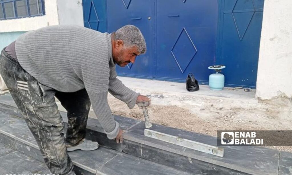 A craftsman in Bosra al-Sham, Daraa, installs tiles as part of a shelter project – December 27, 2024 (Enab Baladi/Waseem al-Adawi)